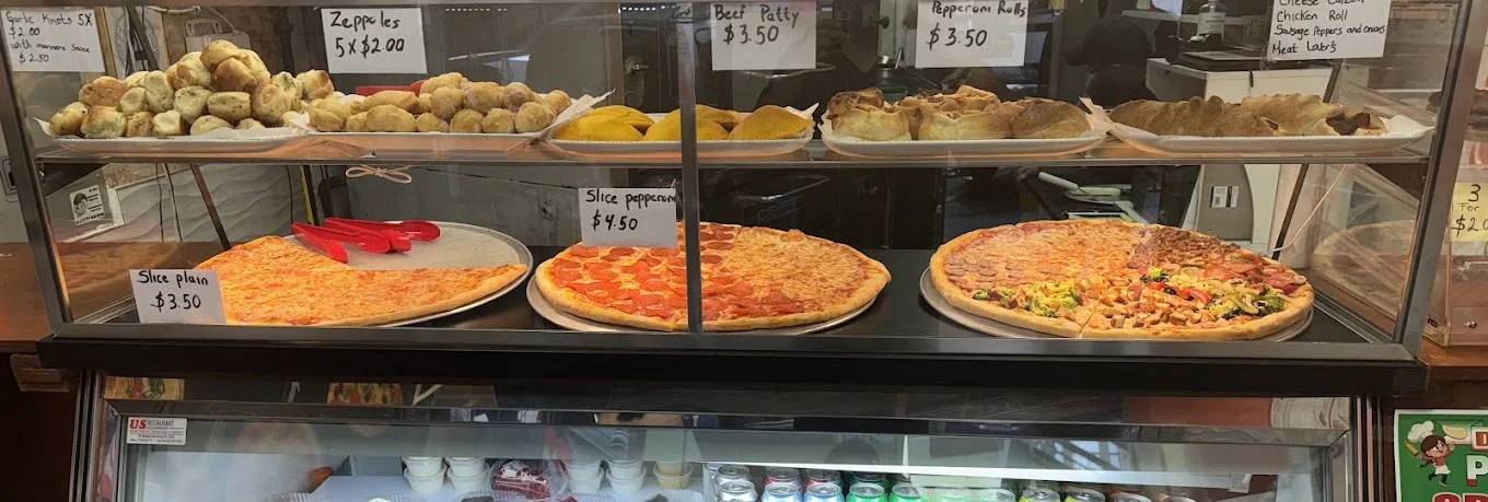 Priced slices and snacks in the display case at Daisy's Pizza 174th St